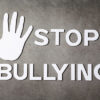 word "stop bullying" with hand sign on dark background